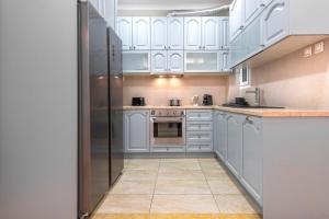 a kitchen with white cabinets and a stainless steel refrigerator at Stylish 2BDR Exarchia Apt with Balcony and Workspace in Athens