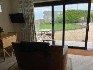 a living room with a couch and a sliding glass door at The Cabin at Ropewalk in St. Agnes