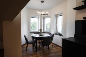 a dining room with a table and chairs and windows at Castle Lakes - Apartamenty in Grzymalin