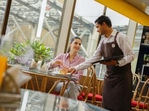 a man serving a woman at a table in a restaurant at Novotel Hyderabad Convention Centre in Hyderabad