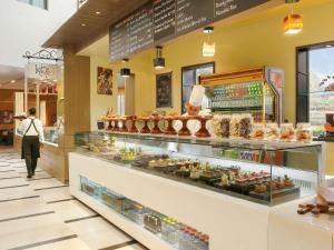 a person walking past a bakery display case at Novotel Hyderabad Convention Centre in Hyderabad