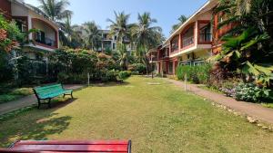 a green bench sitting in the grass next to some buildings at Royale Holiday Villa - 4BHK JAQK Holidays in Baga +39 photos