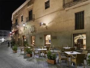 an outdoor patio with tables and chairs in front of a building at NH Collection Cáceres Palacio de Oquendo in Cáceres