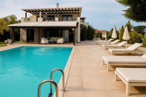 a swimming pool with lounge chairs and a house at White Diamond Villa with Private Pool for group up to 12 in Kamena Vourla