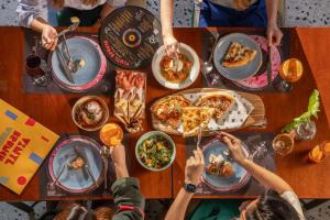 a group of people sitting around a table eating pizza at Siam At Siam Design Hotel Bangkok in Bangkok
