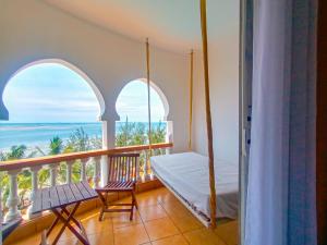 Shanzu Oceanline Apartments and Suites في مومباسا: غرفة نوم مع سرير وشرفه مع المحيط