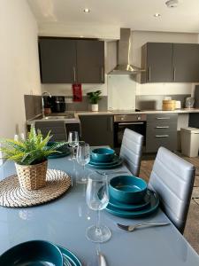 a kitchen with a table with plates and wine glasses at Ideal Wigan Base - 1BR for Cosy Stays in Wigan