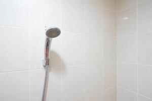 a shower with a shower head in a bathroom at RedDoorz near Mall Ratu Indah 3 in Balangberu