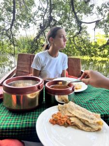 a woman sitting at a table with a plate of food at Travel for Charity Tanzania- Eco Hostel & Volunteer Center in Arusha