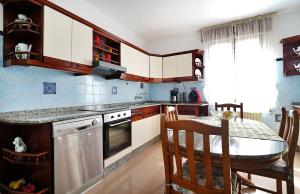 Una cocina con gabinetes blancos y una mesa con sillas. en Casa con jardín en Vilanova de Arousa, en Villanueva de Arosa