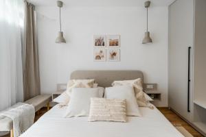 a white bedroom with a bed with white pillows at Geri Harmony Home in Zalaegerszeg