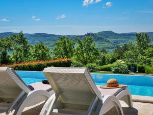 due sedie e un tavolo con un cappello accanto a una piscina di Villa Villa Over the Hilltop by Interhome a Bencani Altre 47 foto