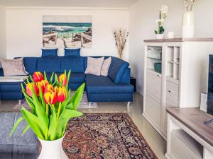a living room with a blue couch and a vase with flowers at Apartment Seezugang & Ski Ossiacher See by Interhome in Bodensdorf