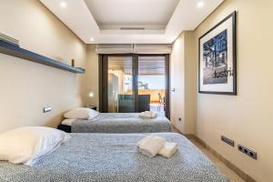 two beds in a room with a window at Estepona East Apartment MAEWEST in Estepona +16 photos