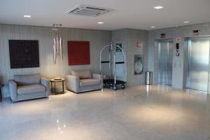 a lobby with two chairs and a elevator in a building at Eldorado Flat in Contagem