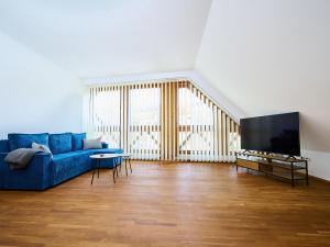 a living room with a blue couch and a flat screen tv at Studio Rosie-Dolní náměstí by Interhome in Rokytnice nad Jizerou