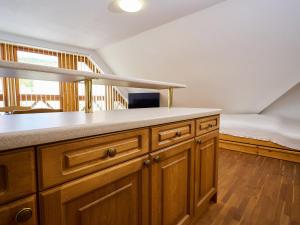 a kitchen with wooden cabinets and a bed in the background at Studio Rosie-Dolní náměstí by Interhome in Rokytnice nad Jizerou