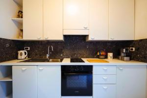 une cuisine avec des armoires blanches et un four à plaques de cuisson dans l'établissement DOLOMIA APARTMENTS PINZOLO vicino alle funivie, à Pinzolo 6 autres photos