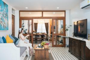 une femme assise sur un canapé dans un salon dans l'établissement LakeLyn Pool Villa 5BR , Free daily housekeeping, à Chiang Mai