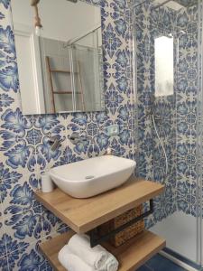 bagno con lavandino e carta da parati blu e bianca di L' Azzurro Mare casa vacanze a Pozzallo