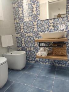un bagno con piastrelle blu e bianche e un lavandino di L' Azzurro Mare casa vacanze a Pozzallo Altre 8 foto
