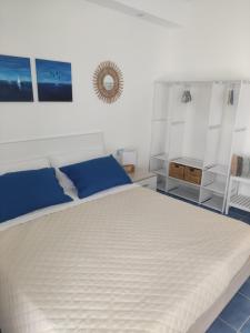 una camera da letto con un grande letto bianco con cuscini blu di L' Azzurro Mare casa vacanze a Pozzallo