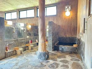 ein großes Badezimmer mit drei Toiletten und einer großen Säule in der Unterkunft 白水温泉竹の倉山荘 in Minami Aso