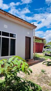 een klein wit huis met een auto ervoor geparkeerd bij The one room in Mto wa Mbu