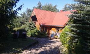 a log cabin with a red roof and a yard at Gospodarstwo Rospuda in Bakałarzewo