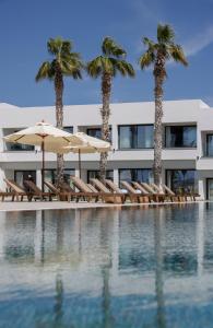 a hotel with chairs and umbrellas next to a swimming pool at Paphos Hills Resort & Spa by Brown Hotels in Paphos City
