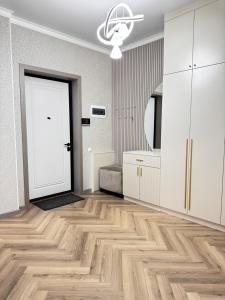 an empty room with a white door and wooden floors at Посуточно 3 комн в ЖК Аль Фараби in Shymkent
