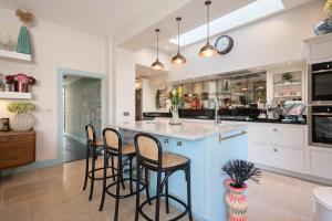 a kitchen with a blue island with four bar stools at Eskbank Terrace Spacious House in Dalkeith