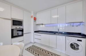 a white kitchen with a washing machine in it at Ocean View! 2-Bedroom Cosy Condo in Portimão +3 photos