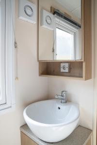 a bathroom with a white sink and a mirror at Camping de Zandput - ZP 237 in Vrouwenpolder +11 photos