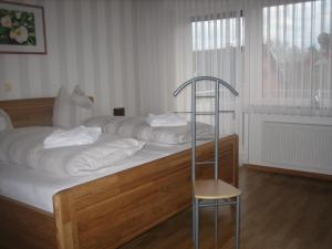 a bed with white sheets and a chair in a room at Haus Herdlitschke in Polle