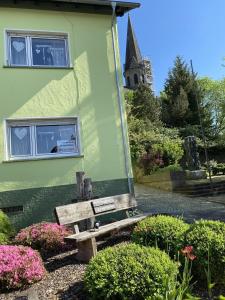 a wooden bench sitting outside of a green building at Ferienhaus Schöndorf in Tholey