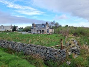 an old stone wall in front of a house at The Weavers Cottage in Leurbost