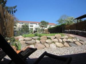 un patio avec deux chaises et un mur de pierre dans l'établissement Ferienhaus Malchow Mit Grill, Garten Und Terrasse, à Malchow
