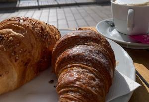 Zwei Croissants auf einem Teller neben einer Tasse Kaffee in der Unterkunft GD Case Vacanza - Suite del Conte - Salento Luxury Private Suite Idromassaggio in Specchia