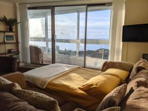 a living room with a couch and a large window at Seaview Sands Beach Apartment in Southbourne