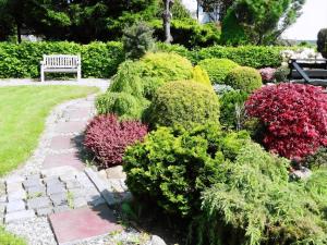 a garden with a bench and colorful bushes at Urlaub Am Meer Im Ferienhaus Mit Sauna in Maasholm +27 photos