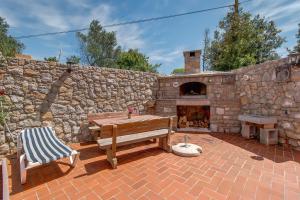 a patio with a wooden table and a stone fireplace at Ferienwohnung Für 2 Personen Ca 40 M Sup2 In Veli Lošinj, Adriaküste Kroatien Kroatische Inseln in Veli Lošinj