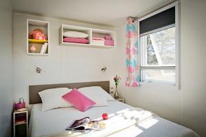 a bedroom with a bed with pink pillows and a window at Ferienhaus In Hohenlychen Mit Grill, Loggia 2 in Lychen