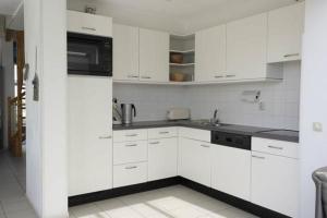 een witte keuken met witte kasten en een magnetron bij Luxusvilla Ooghduyne Mit Privatem Whirlpool in Julianadorp +29 foto's