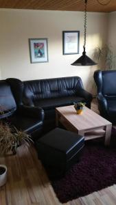 a living room with a black leather couch and a table at Daisy 78 in Wilhelmshaven