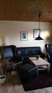 a living room with a black leather couch and a table at Daisy 78 in Wilhelmshaven
