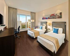 ein Hotelzimmer mit zwei Betten und einem Schreibtisch in der Unterkunft Vivanta Pune, Hinjawadi in Pune