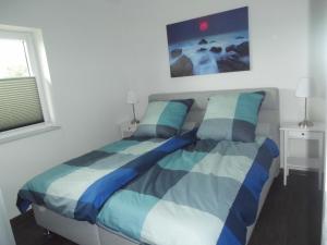 una camera da letto con un letto con lenzuola blu e bianche di Ferienhaus In Sehestedt Mit Garten a Sehestedt