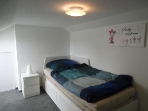 una piccola camera da letto con un letto con lenzuola blu di Ferienhaus In Sehestedt Mit Garten a Sehestedt Altre 15 foto