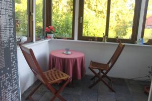 une table avec une nappe rose et deux chaises dans l'établissement Küsterhaus, à Butjadingen
